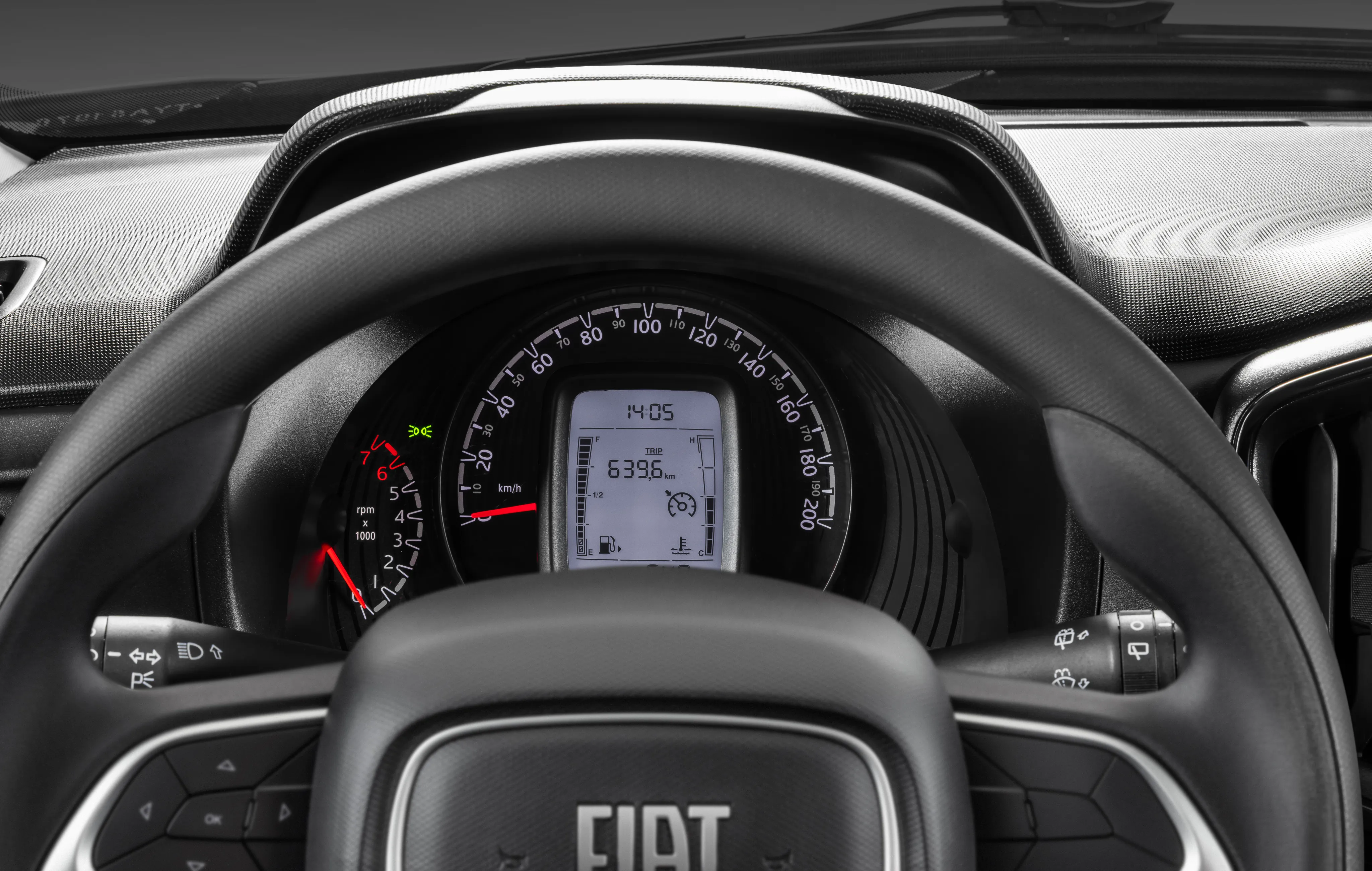 Detalhe do interior de Fiat Mobi com destaque para painel de instrumentos com indicador de troca de marcha, informações sobre consumo e horário.